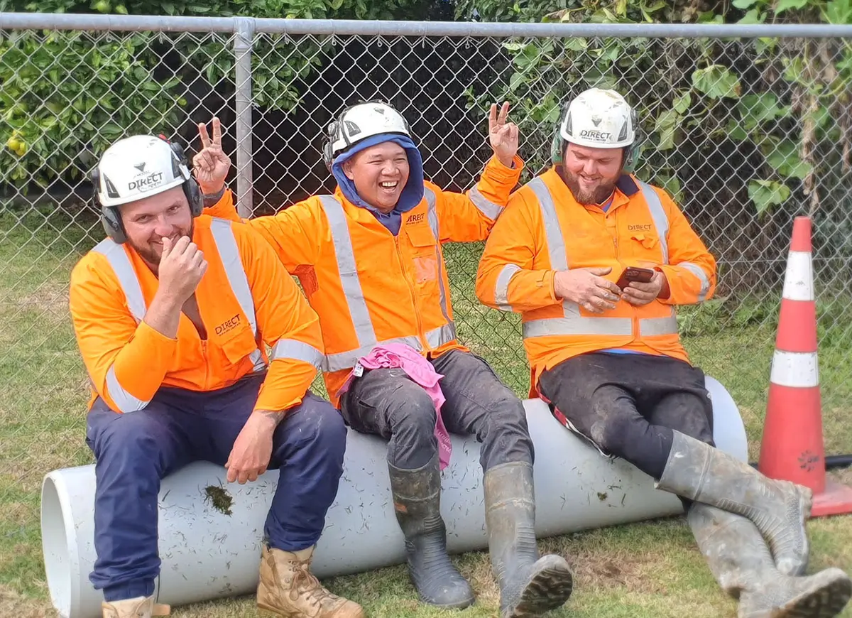 Direct Drains employees wearing high-vis and hardhats, enjoying a break together