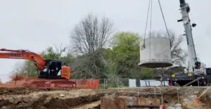 Direct Drains machinery lifting a concrete piece into a dug out area for drainage