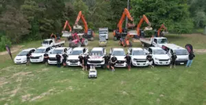 The Direct Drains team standing in front of their vehicle fleet and heavy machinery